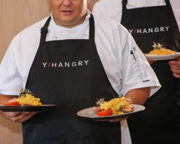 Two chefs holding plates of food, with yhangry aprons